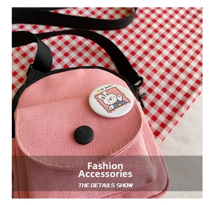 Detailed view of pink canvas bag with cute cartoon rabbit badge and black strap clasp