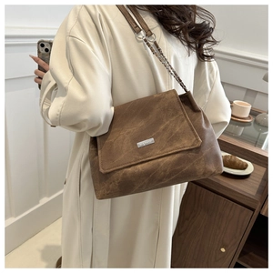 Detail of vintage brown leather shoulder bag with silver chain strap and logo plaque