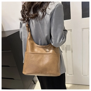 Detail of soft leather texture and adjustable shoulder strap on camel tote bag
