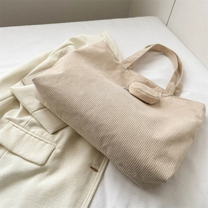 Minimalist beige corduroy tote bag with small round coin purse on a beige blazer