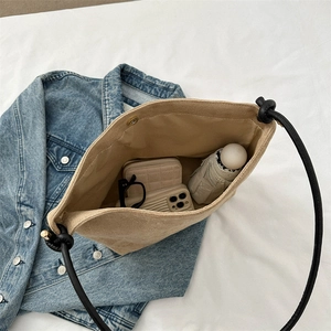 Minimalist beige bucket bag with black rope strap showing its large storage capacity