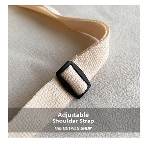 Close-up of adjustable cream canvas strap with durable black plastic buckle detail