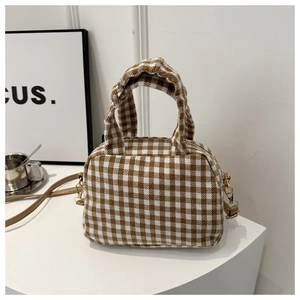 Detail of checkered woven fabric and golden hardware on a vintage crossbody bag