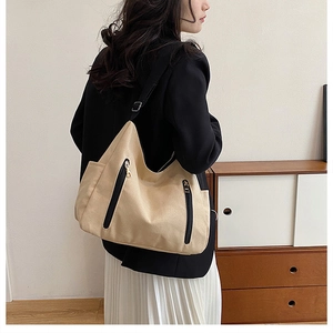 Detail of khaki canvas tote bag with black zipper accents and adjustable strap