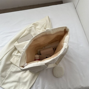 White corduroy tote bag with zipper and mini pouch shown with daily essentials