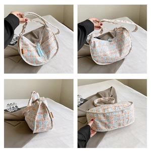Detail of tweed checkered dumpling bag with orange fashion label and crescent shape
