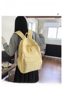 Détail du sac à dos en nylon jaune clair montrant les fermetures éclair doubles