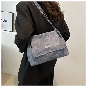 Detail of grey retro shoulder bag with woven chain strap and silver logo plaque