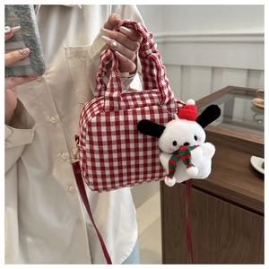Detail of red and white checkered canvas handbag with plush festive dog charm