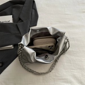 Silver pleated chain bag with grainy texture showing internal storage for phone and wallet