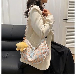Detail of checkered tweed dumpling bag with yellow star plush charm and woven zipper