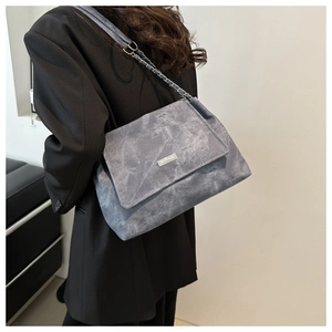 Close-up of grey frosted shoulder bag featuring a metal chain strap and brand plate