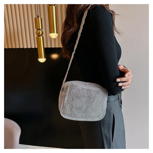Close-up of silver rhinestone crossbody bag worn by a model in a modern interior