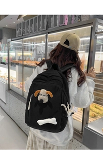 Detail of black corduroy backpack featuring 3D cartoon dog plush and bone charm decoration