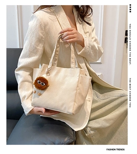 Detail of beige corduroy shoulder bag featuring a cute brown plush monster charm