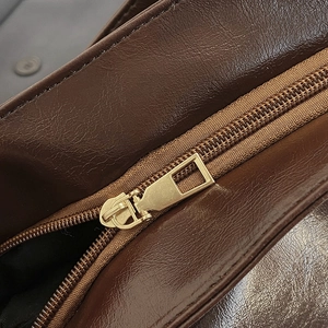 Close-up of golden square zipper on brown oil-wax texture vintage leather backpack