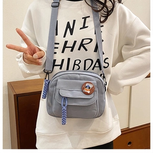 Detail of blue canvas crossbody bag with adjustable strap and cartoon dog badge
