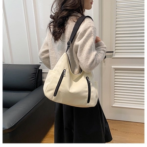 Detail of a large canvas tote bag with black zipper pockets and wide shoulder straps