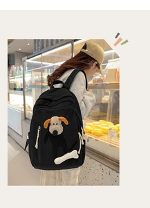 Detail of black corduroy backpack with Gromit plush toy and cute bone charm decoration