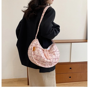 Detail of pink plaid hobo bag with a fashion label and wide strap on model