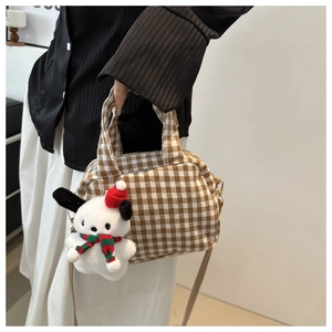 Detail of checkered canvas bowling bag with festive plush dog charm and shoulder strap