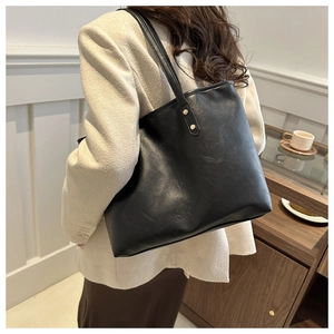 Model view showing the large black faux leather tote bag with gold stud hardware