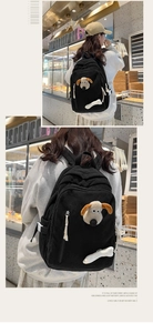 Detail of black corduroy backpack featuring cartoon dog patch and white bone pendant
