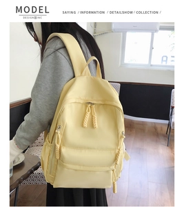 Détail d'un sac à dos en nylon jaune clair avec fermetures éclair à nœuds tressés