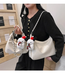 Detail of off-white tote bag with woven chain strap and cute Christmas plush pendant