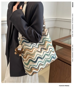 Close-up of knit bucket bag with colorful wavy stripes and wide geometric canvas strap