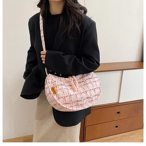 Detail view of pink and white plaid tweed crossbody bag with woven shoulder strap