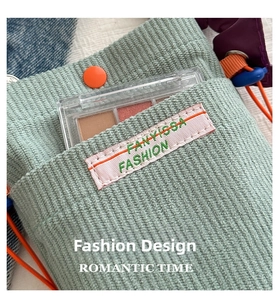 Detail of light green corduroy phone bag showing brand label and textured front pocket