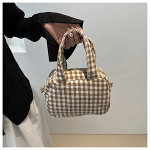 Close-up of brown and white checkered woven bowler bag with metal hardware and zipper