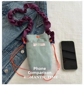 Detail of green corduroy phone bag with purple strap and orange drawstring closure
