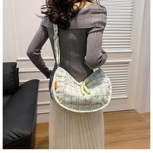 Detailed back view of a plaid corduroy crescent crossbody bag on a model in a casual setting