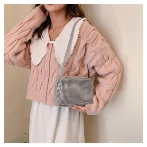 Detail of silver rhinestone crossbody bag with chain strap styled on a pink knit sweater
