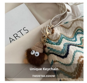 Detailed shot of brown plush pendant with knit hat and colorful embroidered tote bag