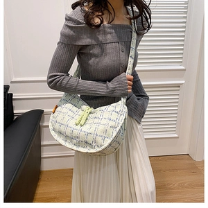 Close-up of green checkered corduroy dumpling bag with fringe tassels on model