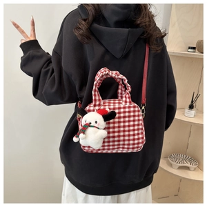 Red plaid crossbody bag with a plush puppy charm shown on a woman's shoulder