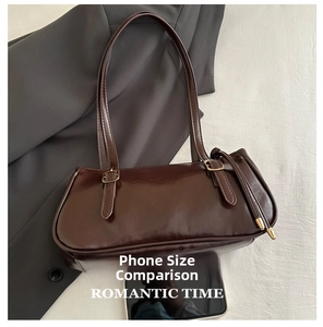 Detailed size comparison of the brown baguette bag with a smartphone on suit fabric