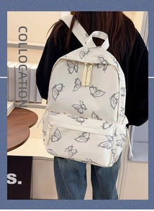 Detail of butterfly print school backpack with woven zipper accents on a model