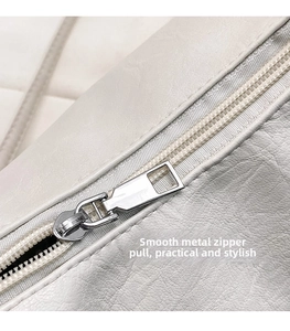 Macro detail of silver hardware puller and nylon zipper on cream leather bag