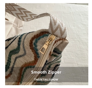Close-up of smooth gold zipper and bohemian wave knit texture on casual shoulder bag
