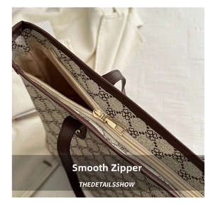 Detail view of smooth metal zipper and brown faux leather handle on floral tote bag