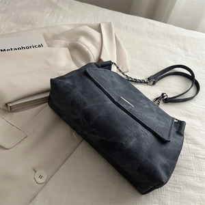 Faded black denim chain shoulder bag with metal logo on elegant white blazer