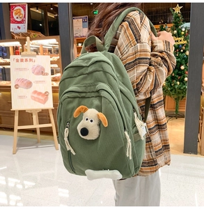 Detail of green corduroy backpack with 3D plush puppy character and bone charm