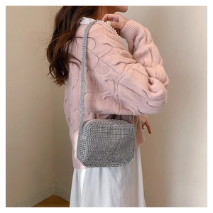 Detail of silver rhinestone mini crossbody bag worn with pink knit sweater for a soft look