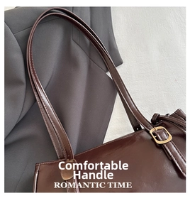 Close-up of the smooth brown leather handle with adjustable gold buckle on a handbag