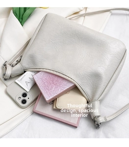 Top view of spacious interior of cream beige pebble leather underarm bag with daily items