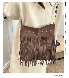Détail d'un sac bandoulière en daim marron avec de longues franges et des oeillets